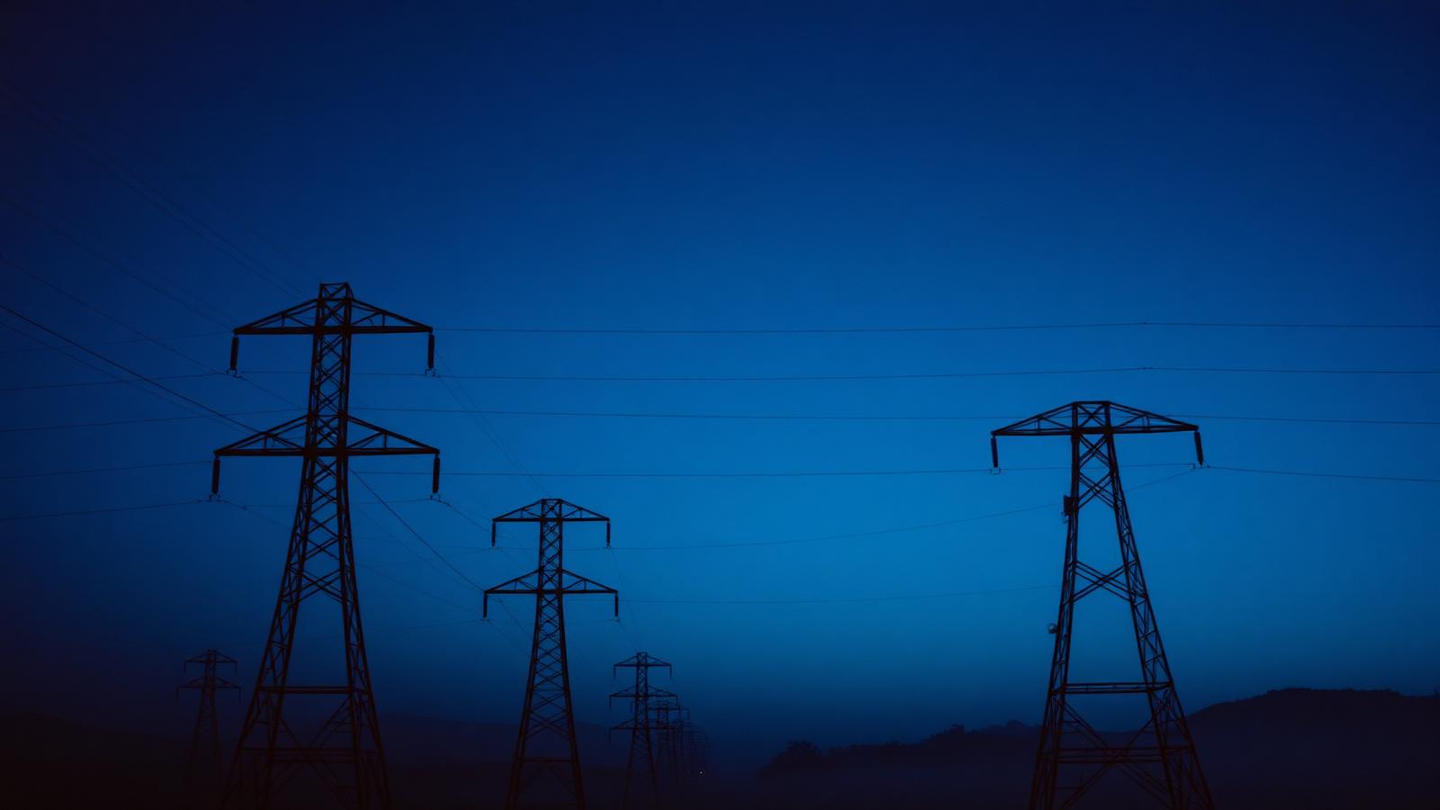 High-voltage transmission towers silhouetted at blue hour